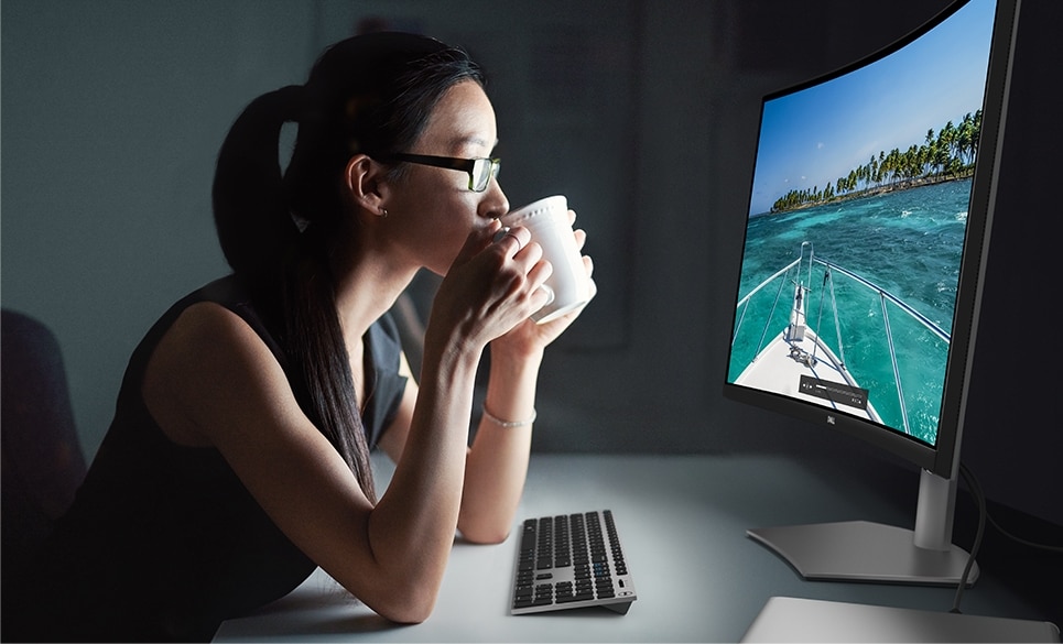Woman with a cup in her hands and lips looking at a Dell S3221QSA Curved Monitor.