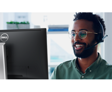 圖片為一位男士戴眼鏡、穿著綠色襯衫且頭戴耳機，正在使用 Dell 顯示器，臉上帶著微笑。
