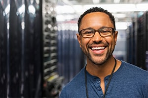 A Man in a server room smiling really big, he is happy to be at work